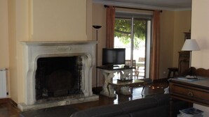 A living room with a fireplace, a television on a stand, a sofa, a table, and a lamp. - Spacious family villa with pool in the heart of green Provence, 4 bedrooms (Saint-Maximin-la-Sainte-Baume)