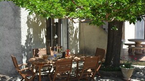 An outdoor dining area with a round wooden table and chairs, surrounded by a tree and a stone bench. - Spacious family villa with pool in the heart of green Provence, 4 bedrooms (Saint-Maximin-la-Sainte-Baume)