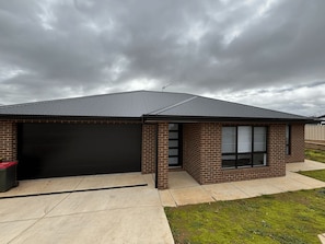A residential building with a garage, brick exterior, and large windows. - Wyoming Getaway Two - Sleeps 8 (Wagga Wagga)
