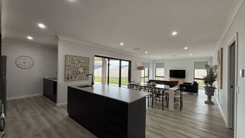 A modern kitchen with a central island, dining area with chairs, and a large window.