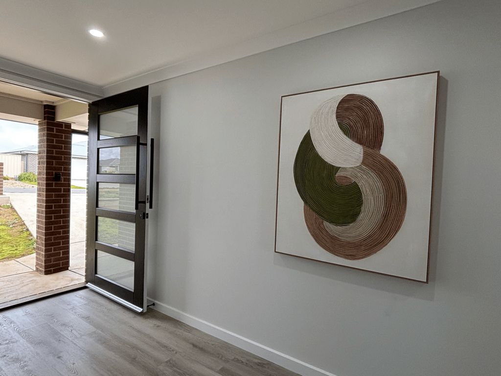 A hallway with a modern abstract painting, a sliding glass door, and a brick pillar.