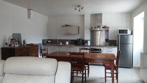 Una cocina moderna con comedor, paredes blancas y un ventanal grande.