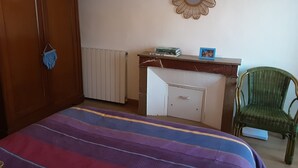 Un dormitorio con cama, armario, escritorio con espejo y silla.