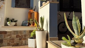A patio with potted plants, a stone wall, and a bicycle in the background. - Fiumicino sea view|Relax&Comfort Near the airport and Fiera di Roma (Isola Sacra)