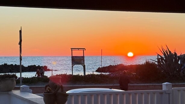 A sunset view from a balcony overlooking the sea, with a white fence and potted plants. - Fiumicino sea view|Relax&Comfort Near the airport and Fiera di Roma (Isola Sacra)