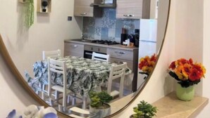A compact kitchen with modern appliances, a dining area, and a mirror reflecting the space. - Fiumicino sea view|Relax&Comfort Near the airport and Fiera di Roma (Isola Sacra)