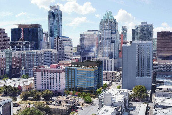 Un paysage urbain avec des immeubles modernes de grande hauteur, dont un hôtel reconnaissable à son enseigne bien visible.