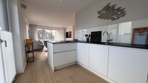 A modern kitchen with a central island, white cabinetry, and a large window providing natural light. - "Baltic Sea happiness"... The sound of the sea included! (Dahme)