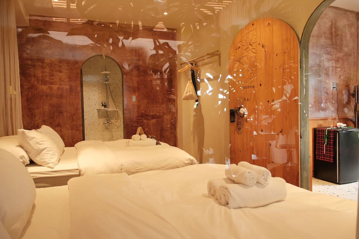 A hotel room with two beds, a wooden wall, a shower, and a minibar.