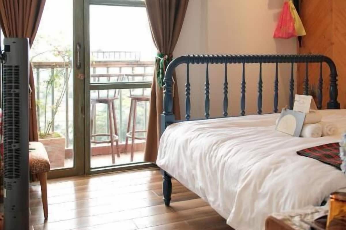 A bedroom with a bed, a heater, a window with curtains, and a view of the outdoors.