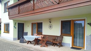 A building with a balcony, a table with chairs, and a door with a window.