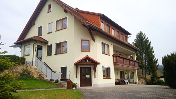 A two-story building with a balcony, a staircase, and a paved driveway.