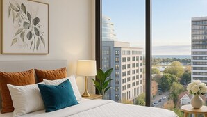 Camera d'albergo con un letto grande, un comodino con una lampada, un quadro appeso alla parete e vista sulla città.