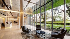 Una hall moderna con una reception, posti a sedere in pelle, un tappeto decorato e ampie finestre che danno sul panorama esterno.