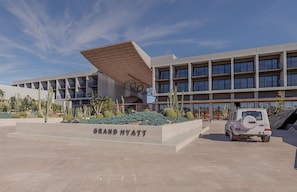A Grand Hyatt hotel with a modern architectural design, featuring a prominent entrance with a unique roof structure and a spacious courtyard with cacti and landscaping.