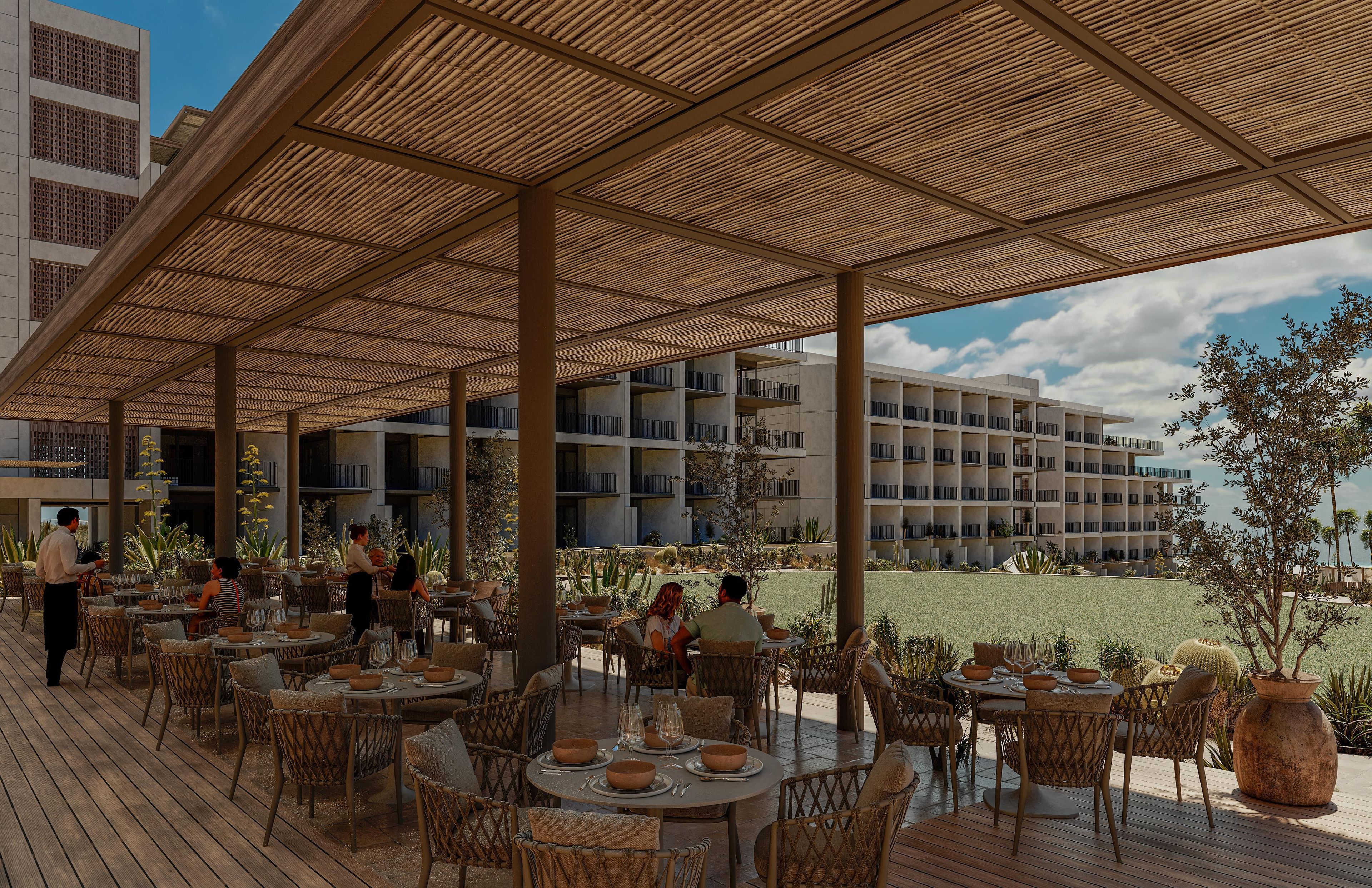 Un espacio exterior techado para comer con muebles de mimbre y vistas a un edificio moderno.