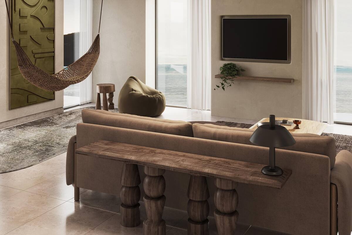 Un salon moderne avec un canapé, un fauteuil poire, un hamac, un téléviseur et une vue sur la mer.
