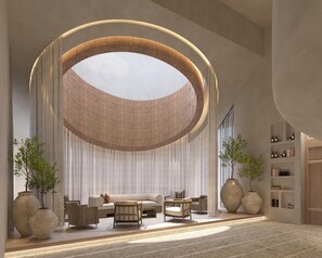 Un interior modern amb una gran estructura circular al sostre, un conjunt de sofàs i dos grans vas.