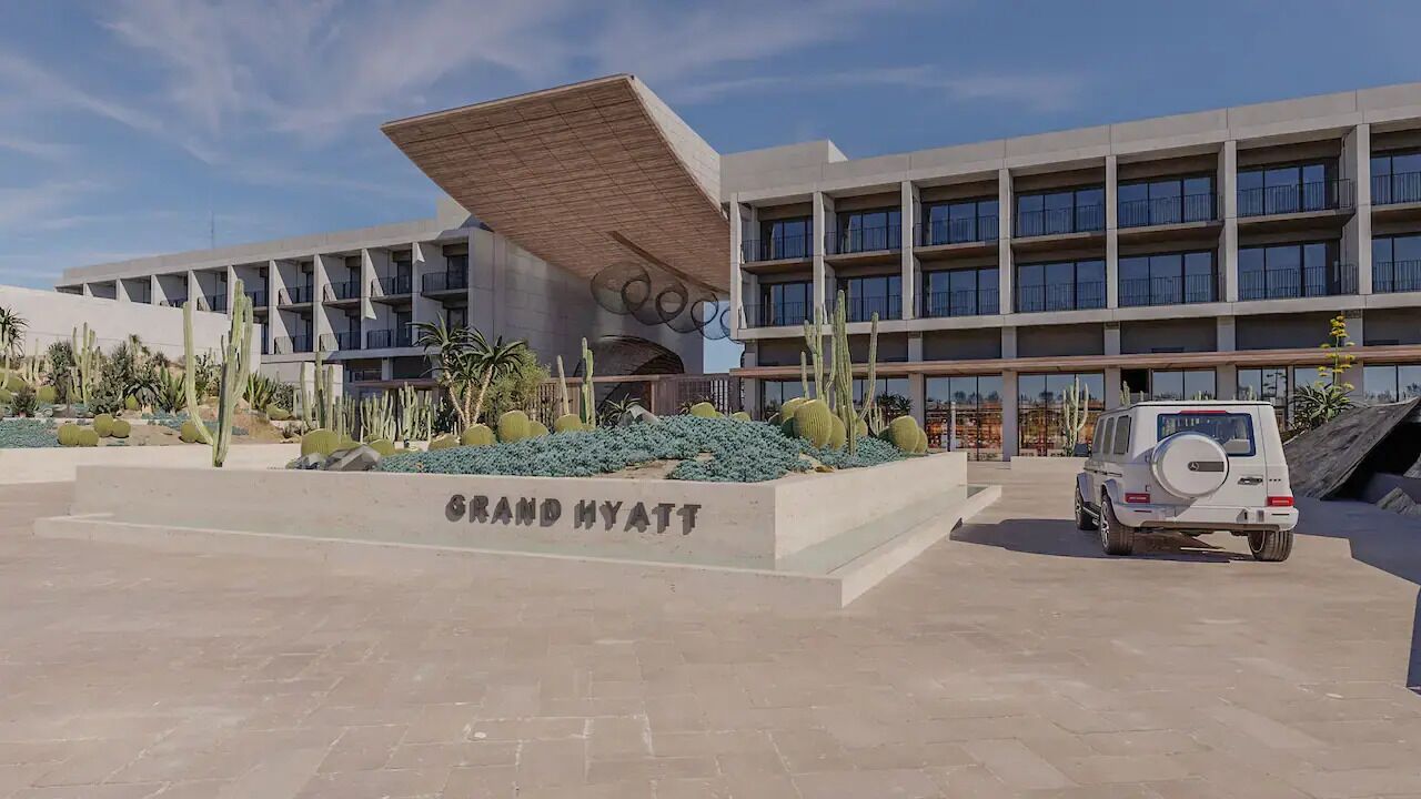 A Grand Hyatt hotel with a modern design, featuring a large parking area and a distinctive architectural structure with a slanted roof.