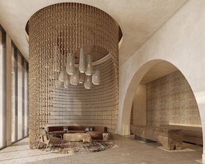 Un interior modern amb una paret de textura única, una zona de seients amb sofàs i una catifes, i una gran porta d'arc.