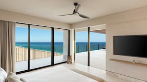 Quarto de hotel com cama grande, televisão e varanda com vista para a praia e oceano.