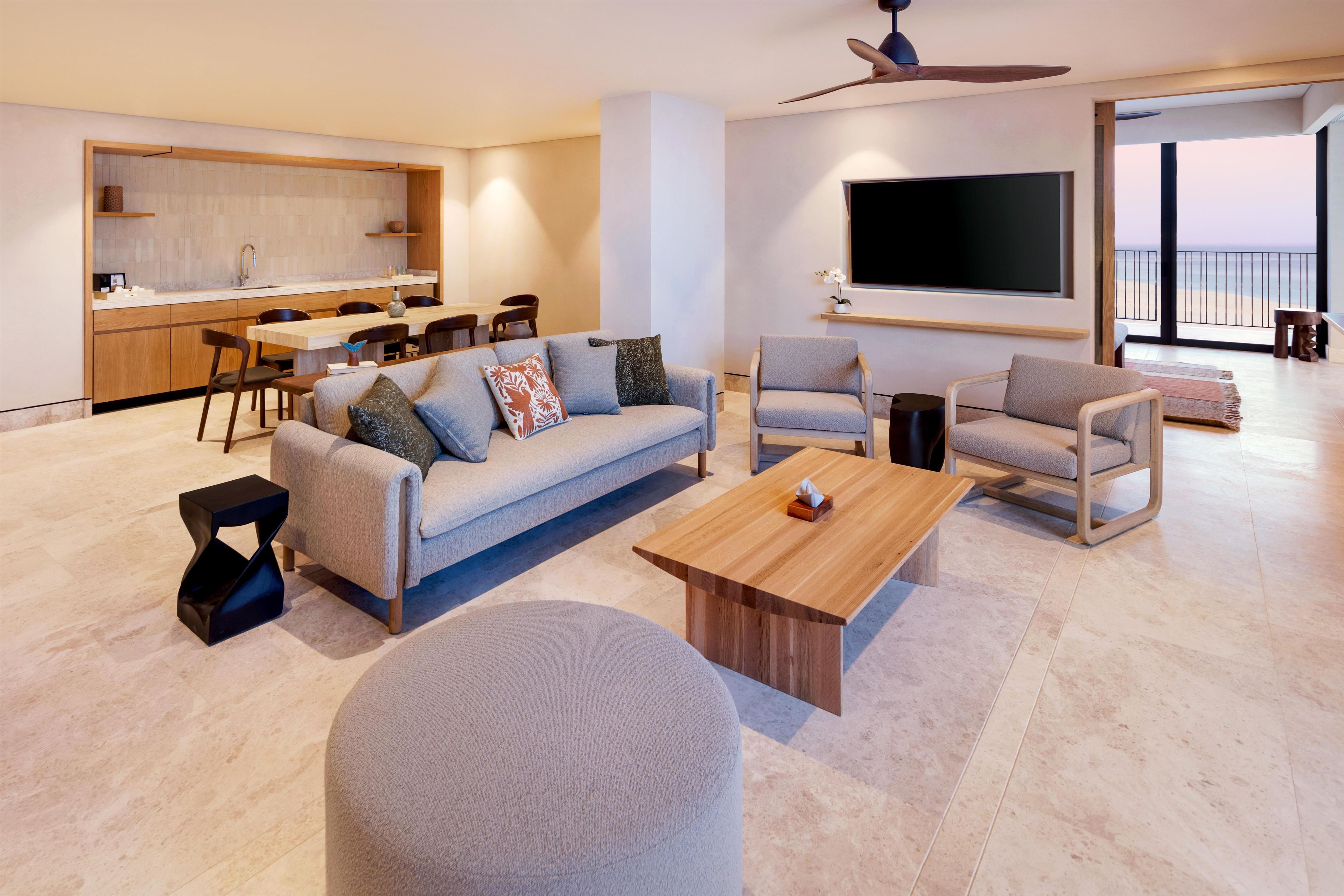 A modern living room with a sofa, armchairs, a coffee table, and a TV.