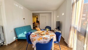 Een eethoek met een ronde tafel, blauwe stoelen en een bank.
