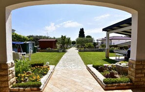A pathway leading to a covered area with a stone wall, a small shed, and a bench. - Bright flat with sea view terrace (Umag)