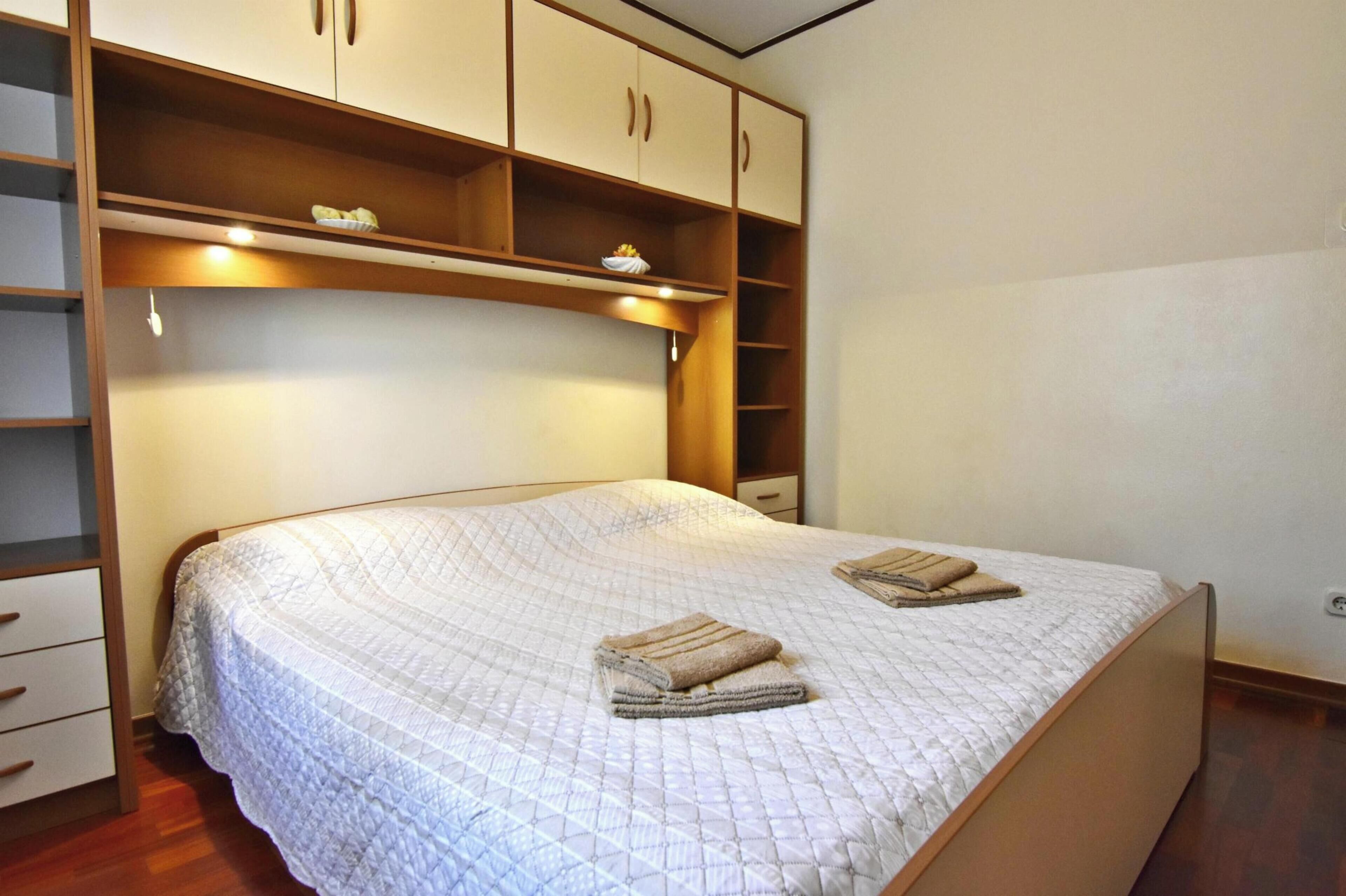 Quarto com cama, guarda-roupa embutido e mesa de cabeceira.