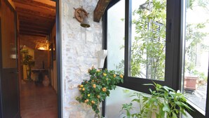 A stone wall, a potted plant with yellow flowers, and a view of greenery outside. - Comfy apartment with terrace and BBQ (Umag)