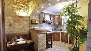 A rustic kitchen with stone walls, wooden furniture, and a built-in stove. - Comfy apartment with terrace and BBQ (Umag)