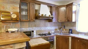 A kitchen with wooden cabinets, a microwave, a stove, and a radio. - Comfy apartment with terrace and BBQ (Umag)