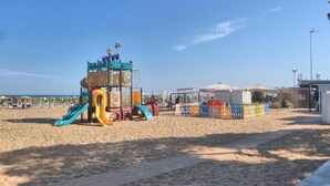 Een strand met een speeltuin, inclusief glijbanen en speeltoestellen, en een toren voor de strandwacht.