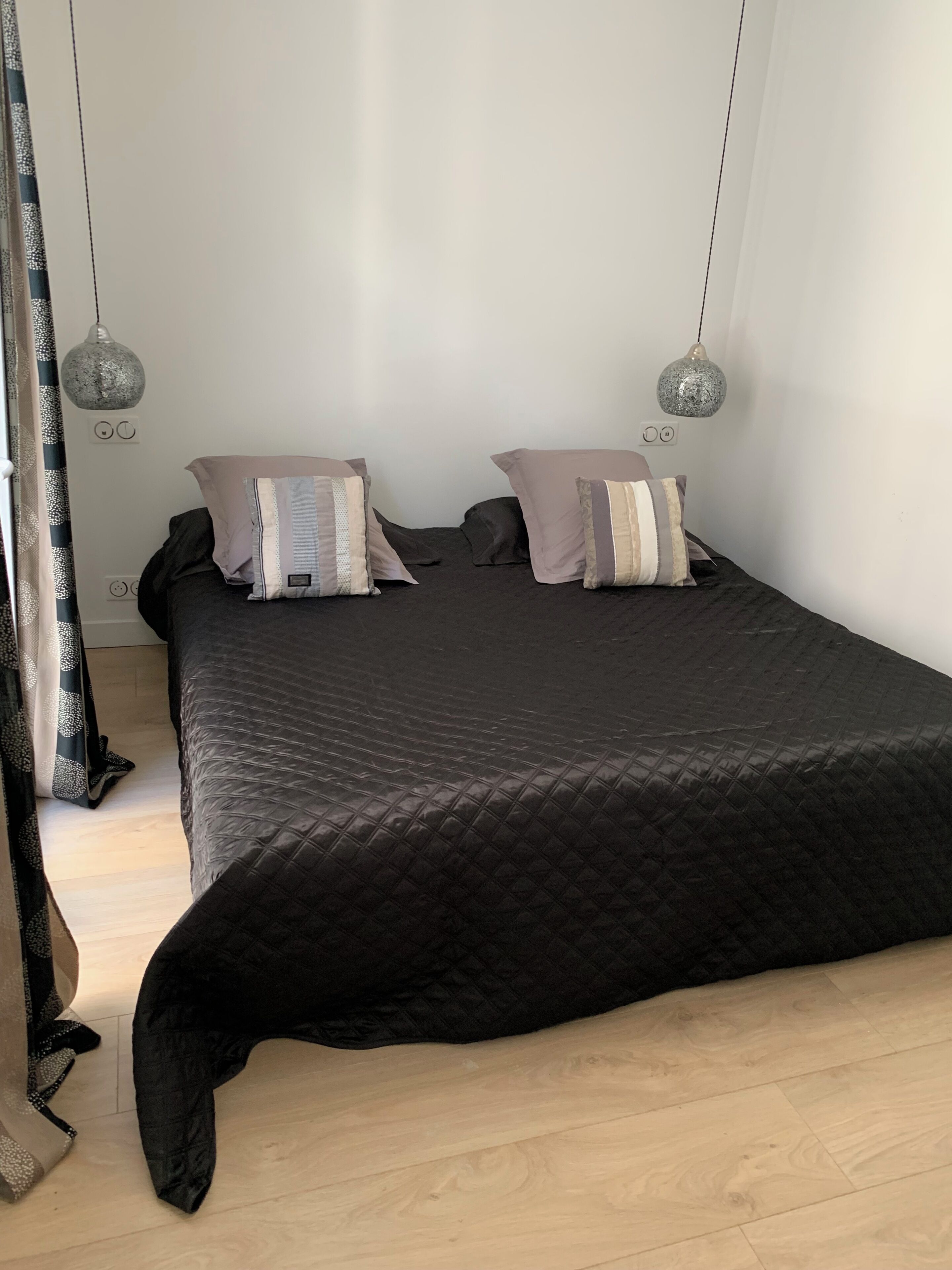 Um quarto com cama, duas luminárias de cabeceira e cortina.