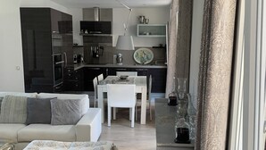 Een moderne woonkamer met een bank, een salontafel en een eethoek met een tafel en stoelen.
