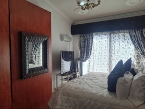 Un dormitorio con cama, televisor, armario y espejo.