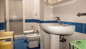 Badeværelse med bruser, toilet, bidet, vask og en grøn skraldespand.