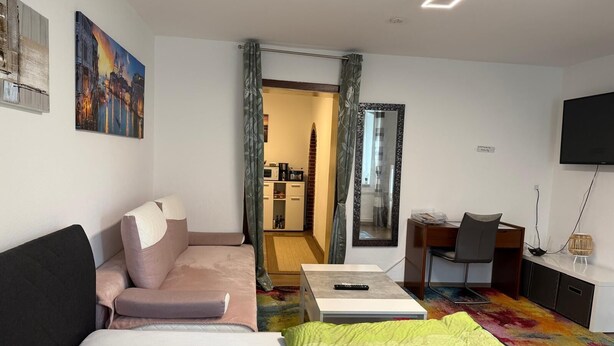 Ett modernt hotellrum med en säng, soffa, skrivbord och en tv.