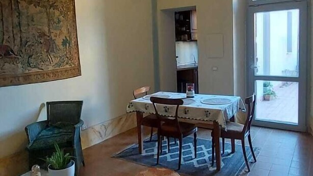 Ein geräumiges Wohnzimmer mit Essbereich, einem großen Fenster und einer Decke mit freiliegenden Balken.