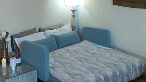 Ein Schlafzimmer mit Bett, Nachttisch, Lampe, Wandregal und einem Gemälde.