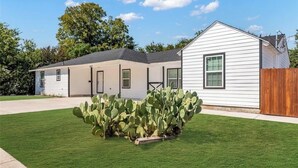 A single-story house with a front yard, a wooden fence, and a cactus plant. - Cozy Retreat on Dana Drive (Haltom City)