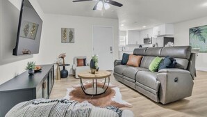 A modern living room with a sofa, a coffee table, and a TV mounted on the wall. - Cozy Retreat on Dana Drive (Haltom City)
