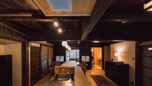 A modern kitchen with a central island, wooden beams, and a view into the dining area.