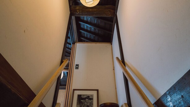 A wooden staircase with a hanging light fixture.
