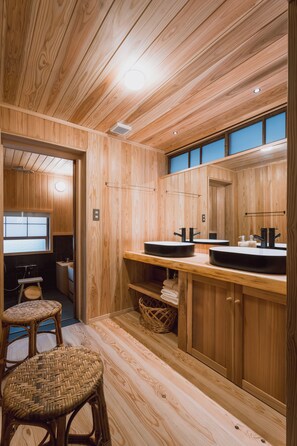 A wooden interior with a kitchen area, two stools, and a window.