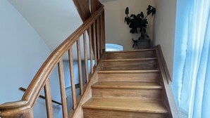 A wooden staircase with a handrail, leading to a landing with a potted plant.