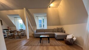 A loft-style living room with a sofa, coffee table, and a dining area with chairs.