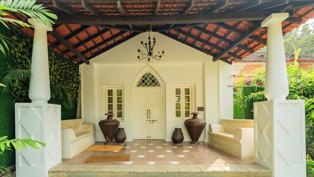 A covered entrance with a tiled floor, two large vases, and a white door with a window. - ELIVAAS Maison 10 Luxe 4 BHK Villa  (Siolim)