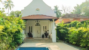 A building with a white facade, a tiled roof, and a pool in front. - ELIVAAS Maison 10 Luxe 4 BHK Villa  (Siolim)