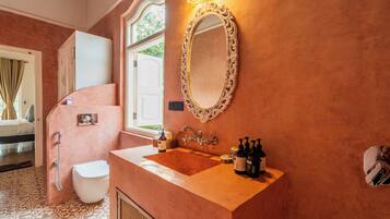 Un baño con lavamanos, espejo y artículos de aseo.